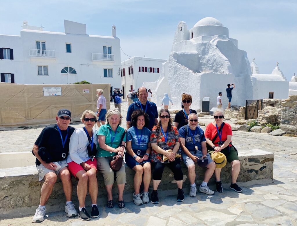 photo of people with the paraportiani church mykonos in the background