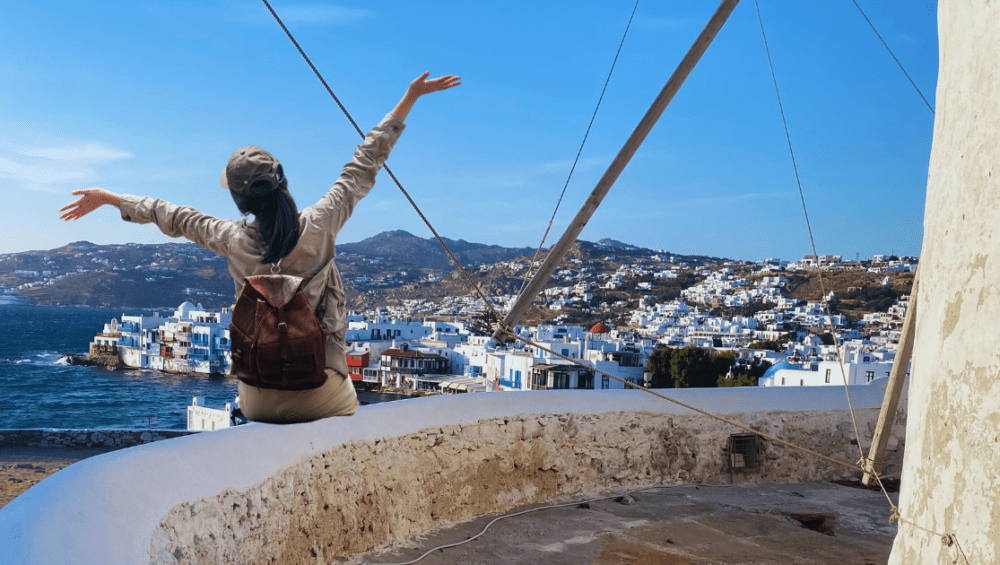 Girl seating on the wind mill in Mykonos during the Mykonos solo adventure package.