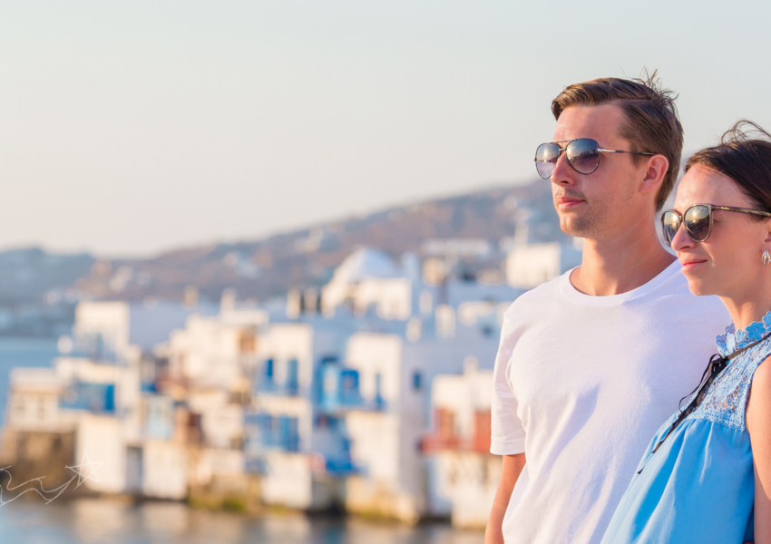 Couple standing with Mykonos Little Venice in the background.